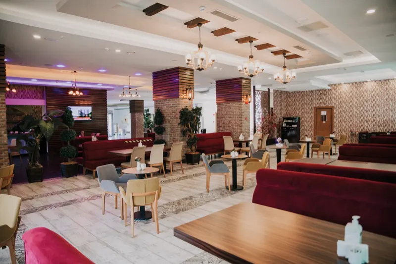 Otelin restoranı: masalar, bordo koltuklar ve avizeler