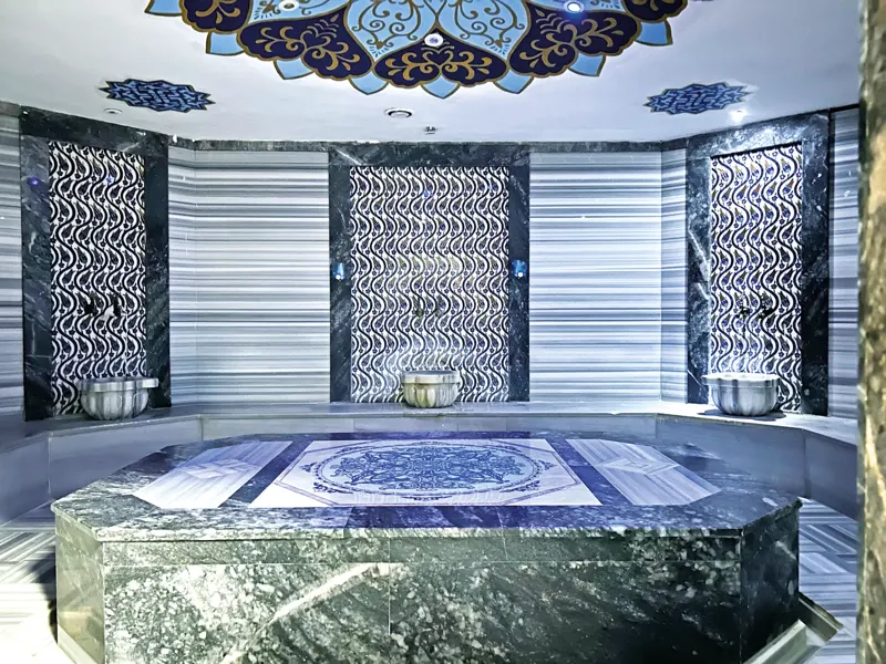 Turkish hammam with a marble heated platform, basins and a tile-patterned dome