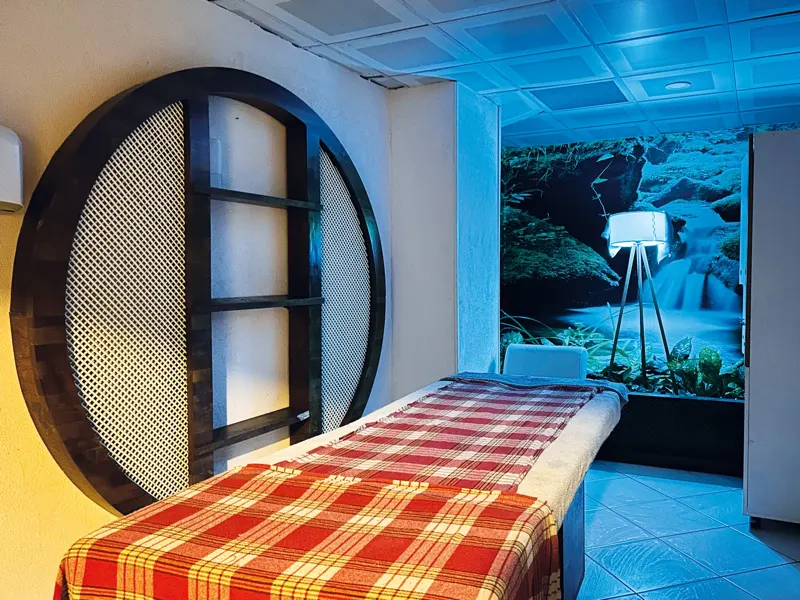 Massage room with a massage table, a round lattice screen and a waterfall mural